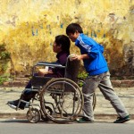 web3-helping-people-boys-pushing-push-wheelchair-disabled-shutterstock_168063155-john-bill-ai1